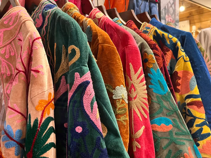 Vestes colorées avec des motifs variés suspendues sur des cintres.