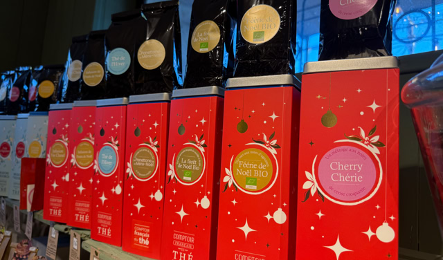Boîtes de thé rouges alignées sur une étagère, avec des étiquettes colorées et des motifs de flocons de neige.