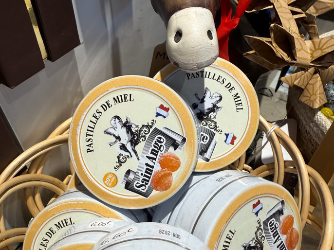 Panier contenant plusieurs boîtes rondes avec une illustration d'âne et l'inscription "Pastilles de Miel", accompagné d'une peluche d'âne.