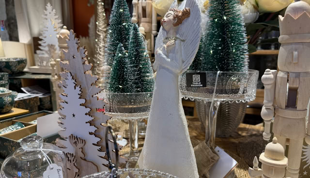 Décorations de Noël comprenant des sapins miniatures verts, une figurine blanche, et divers ornements en bois sur une table.