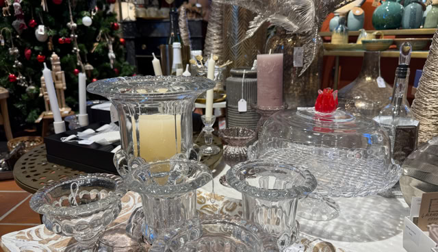 Verrerie décorative sur une table avec des bougies et un sapin de Noël en arrière-plan.