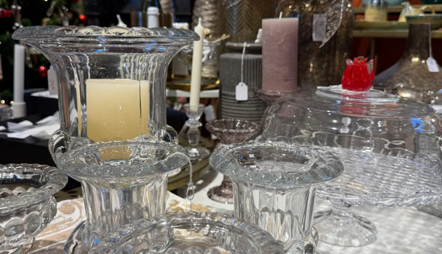 Verrerie décorative sur une table, avec des bougies et des décorations de Noël en arrière-plan.