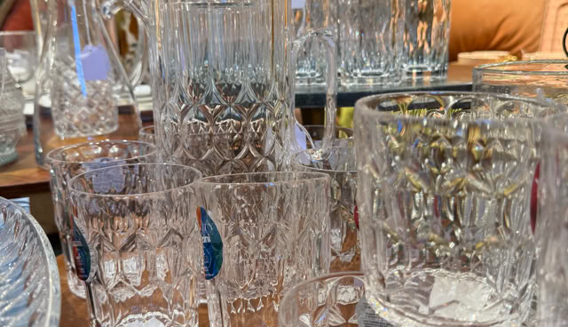 Verres en cristal sur une table avec des étiquettes, entourés d'autres objets décoratifs.