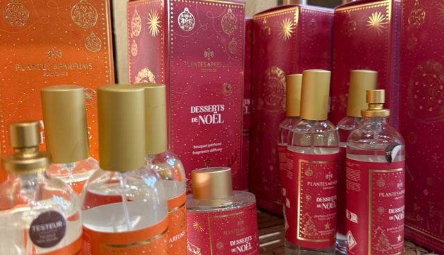 Flacons de parfum et boîtes rouges et orange sur une étagère en bois.