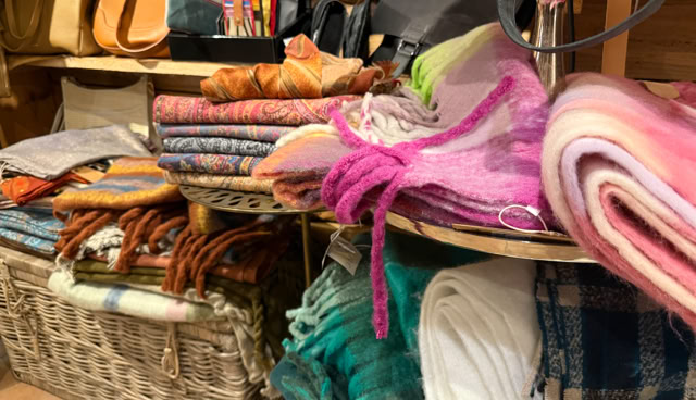 Étagères remplies de couvertures colorées et de sacs en cuir dans un magasin.
