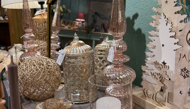 Objets décoratifs sur une table, comprenant des bougeoirs, des vases en verre, un miroir doré, et un arbre en bois découpé.