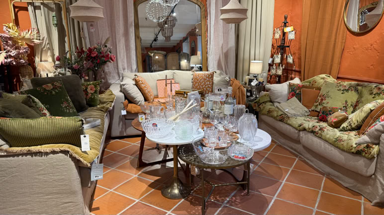 Salon avec deux canapés, une table basse avec des verres et des assiettes, des coussins colorés, et des décorations florales.