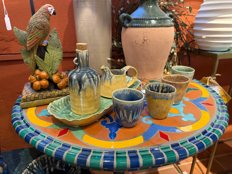 Salon avec deux canapés, une table basse avec des verres et des assiettes, des coussins colorés, et des décorations florales.