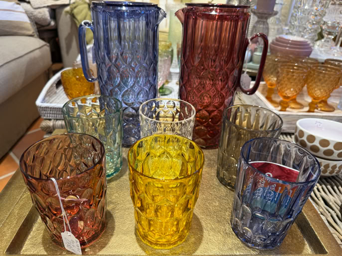 Carafes et verres colorés en verre texturé sur un plateau doré.
